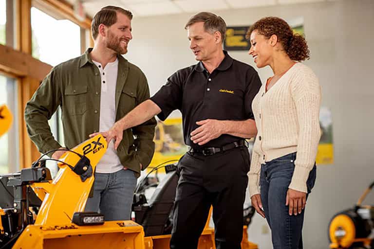 man and woman inspecting snow blower with a dealer representative